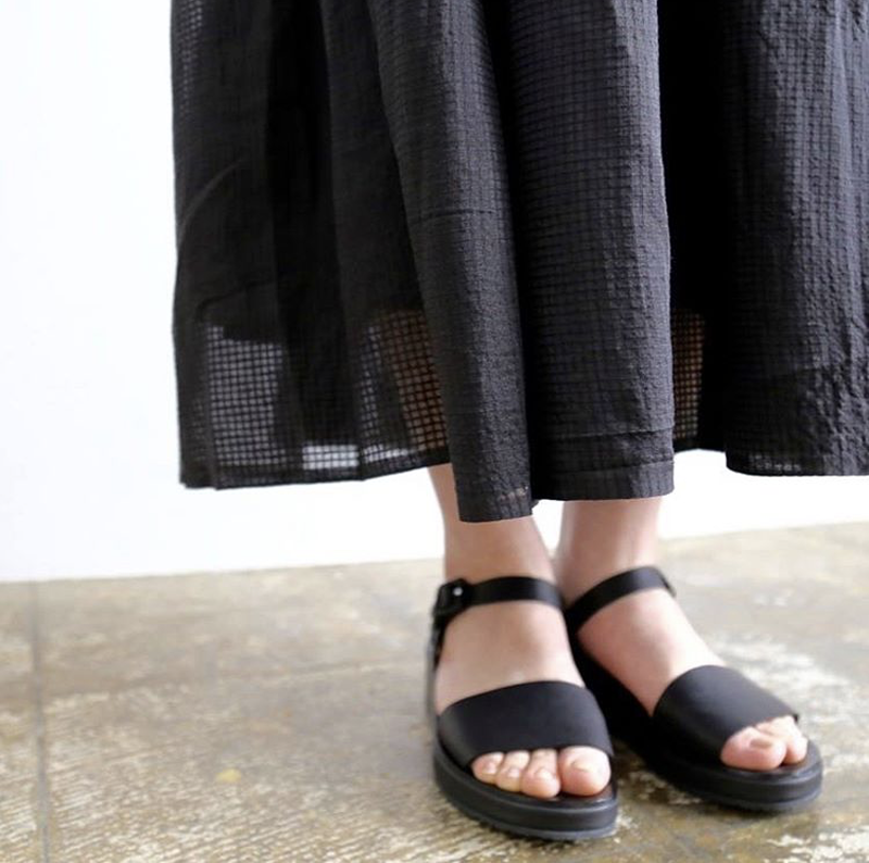 Woman in long navy skirt and Tracey Neuls navy flat sandals with ankle strap