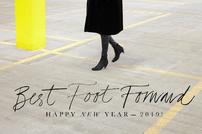 woman in black walking on grey floor with neon bollard. Happy New Year message