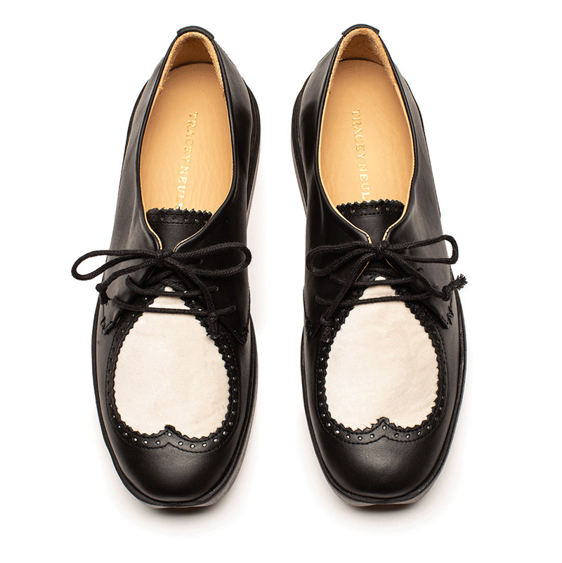 A pair of black and white lace up women's brogue shoes with white heart detailing by designer Tracey Neuls
