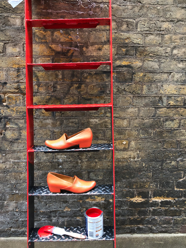 Red shoes by designer Tracey Neuls on a ladder with red paint