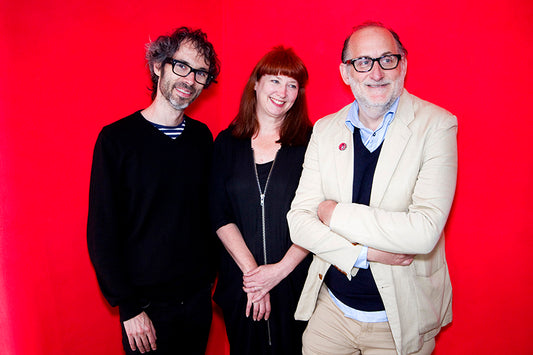 A portait of James Rhodes, shoe designer Tracey Neuls and James Rhodes manager Denis Blais standing in front of a red wall