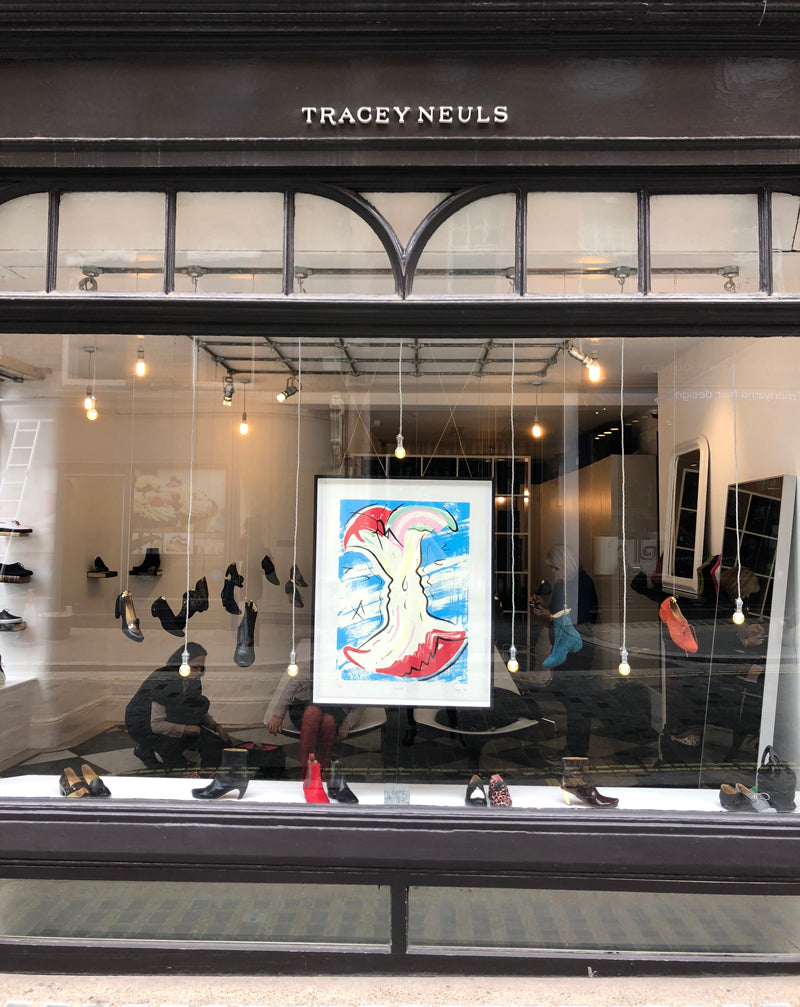 Shop front with framed print by artist Hannah Bays hanging in window