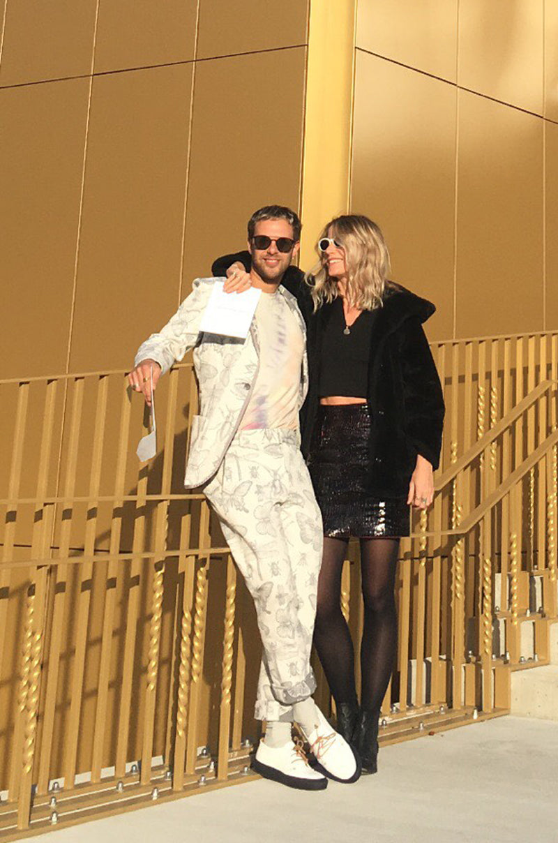 Artist Laurence Owen wearing white Tracey Neuls lace up sneakers and white suite, with girl in black