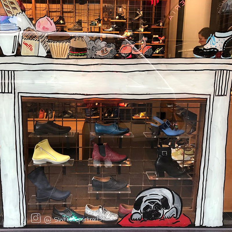 Shoe shop window painted like a white fireplace with painted dog